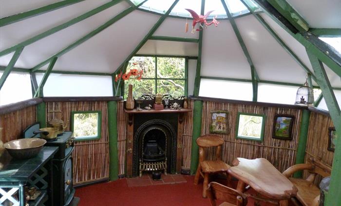 The interior of a play house in the garden, featuring home made child size furniture, a fire place and cooker